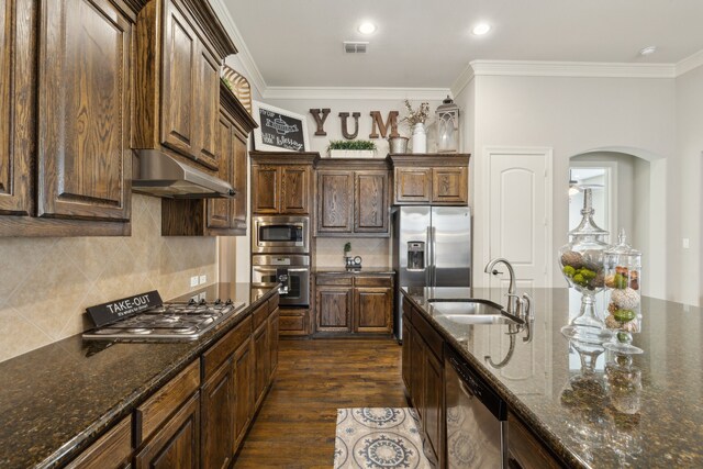 kitchen with a sink, arched walkways, stainless steel appliances, under cabinet range hood, and visible vents