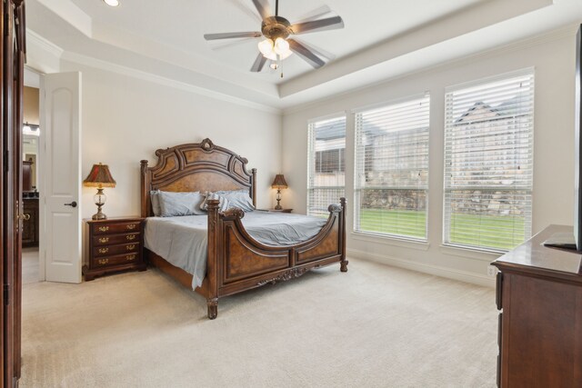 bedroom with crown molding, multiple windows, a tray ceiling, and light carpet