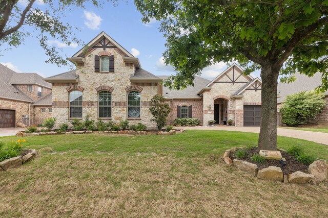 view of front of home featuring roof with shingles, driveway, a front lawn, and stone siding