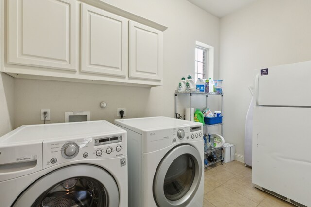 clothes washing area with cabinet space, light tile patterned flooring, and washing machine and clothes dryer