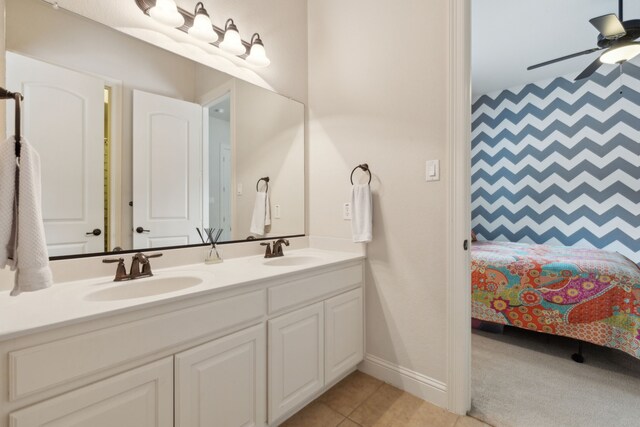 full bath with double vanity, a ceiling fan, baseboards, and a sink