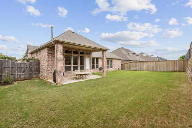 back of house with a yard, brick siding, a patio, and a fenced backyard
