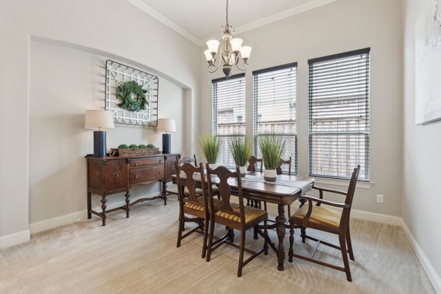 dining space with an inviting chandelier, baseboards, ornamental molding, and light colored carpet