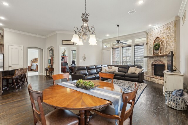dining space featuring dark wood-style flooring, a fireplace, arched walkways, visible vents, and ornamental molding