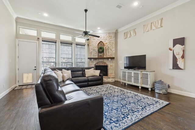 living area with crown molding, ceiling fan, a stone fireplace, baseboards, and visible vents