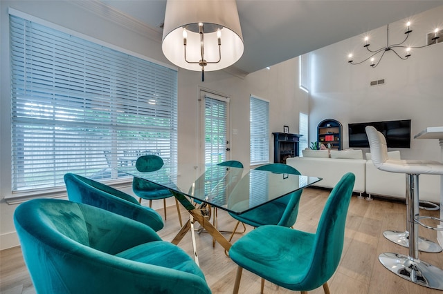8909 White Pine Ln, Dallas, TX 75238 - dining room featuring healthy amount of natural light, crown molding, light wood-style flooring, a fireplace, and a chandelier