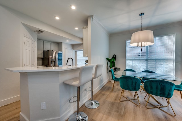 8909 White Pine Ln, Dallas, TX 75238 - kitchen with stainless steel refrigerator with ice dispenser, baseboards, a sink, light countertops, and a kitchen bar