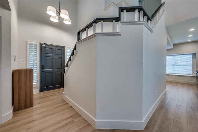8909 White Pine Ln, Dallas, TX 75238 - entrance foyer featuring a towering ceiling, a chandelier, light wood-style flooring, baseboards, and stairs