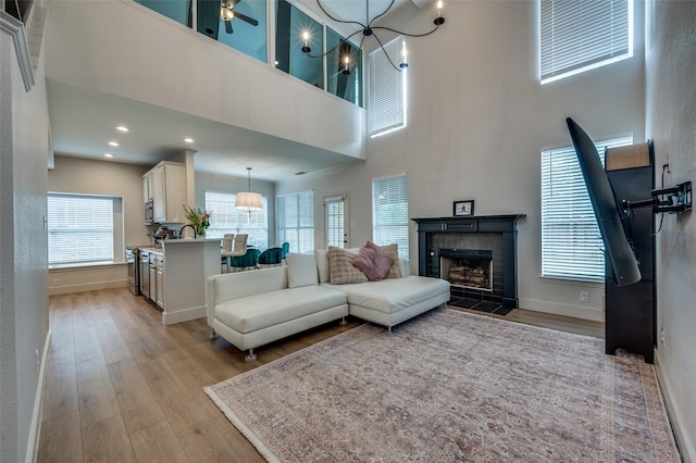 8909 White Pine Ln, Dallas, TX 75238 - living area featuring light wood finished floors, a tile fireplace, a high ceiling, baseboards, and a chandelier