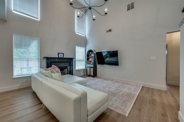 8909 White Pine Ln, Dallas, TX 75238 - living room featuring a towering ceiling, a chandelier, baseboards, light wood-style flooring, and a tiled fireplace