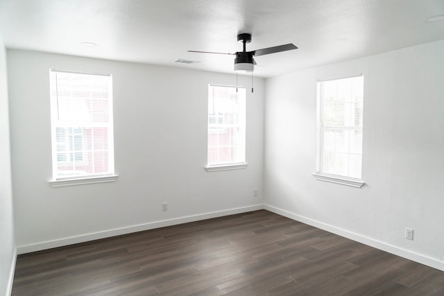 unfurnished room with baseboards, a ceiling fan, dark wood-style flooring, and visible vents