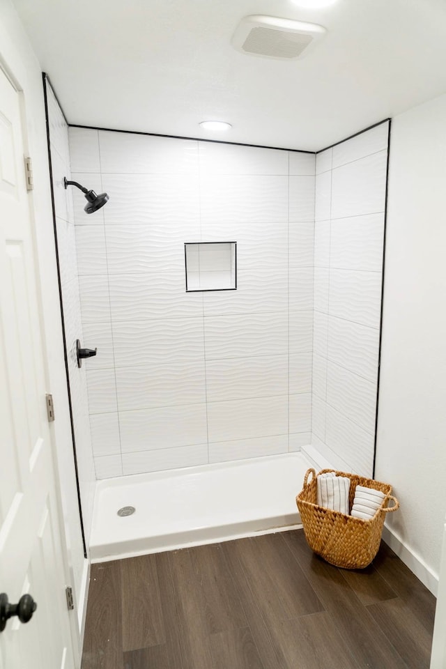 bathroom featuring wood finished floors and a tile shower