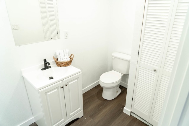 bathroom with toilet, baseboards, wood finished floors, and vanity