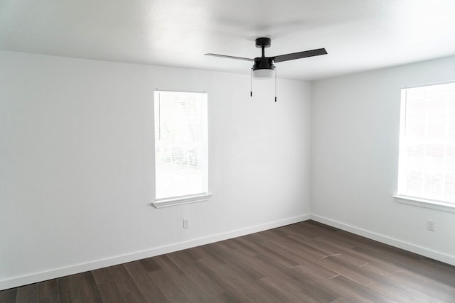 spare room featuring baseboards, a ceiling fan, and dark wood finished floors