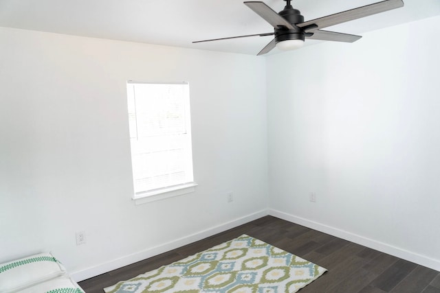unfurnished room featuring baseboards, a ceiling fan, and dark wood finished floors