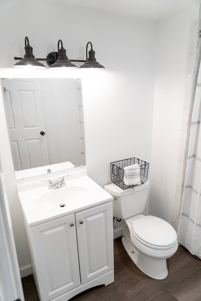 bathroom featuring toilet, wood finished floors, and vanity