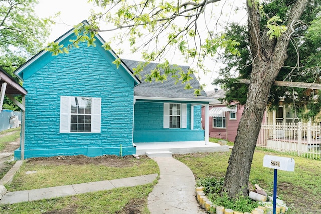 bungalow-style house featuring a porch, a front yard, brick siding, fence, and a shingled roof