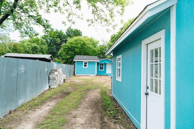 view of home's exterior with fence, an outdoor structure, and dirt driveway