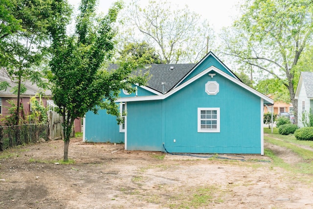 back of property featuring fence and a shingled roof