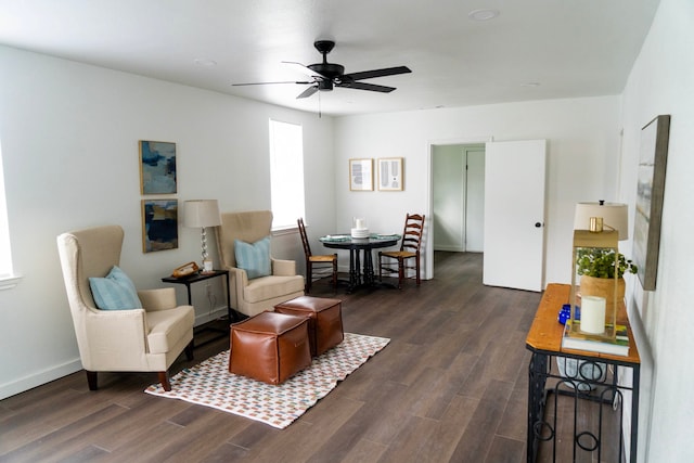 living area featuring baseboards, a ceiling fan, and dark wood-style floors