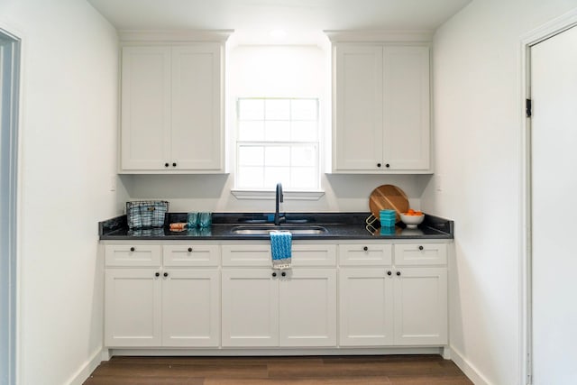 kitchen featuring a sink, dark countertops, white cabinetry, and dark wood-type flooring
