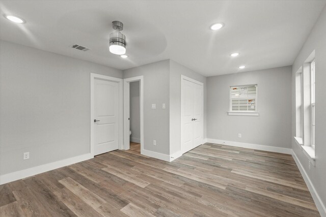 unfurnished bedroom featuring visible vents, wood finished floors, baseboards, a closet, and recessed lighting