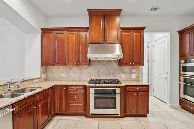 kitchen with visible vents, under cabinet range hood, tasteful backsplash, a sink, and stainless steel appliances
