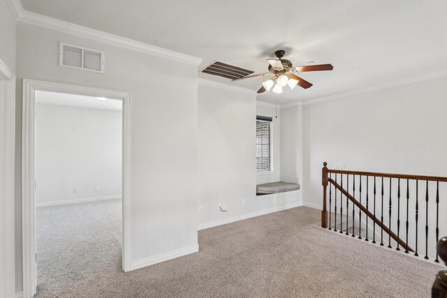 spare room featuring carpet floors, a ceiling fan, baseboards, visible vents, and ornamental molding