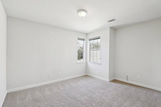 unfurnished room featuring baseboards, visible vents, and carpet