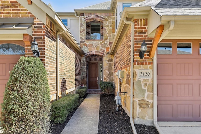 doorway to property featuring brick siding, roof with shingles, and stone siding