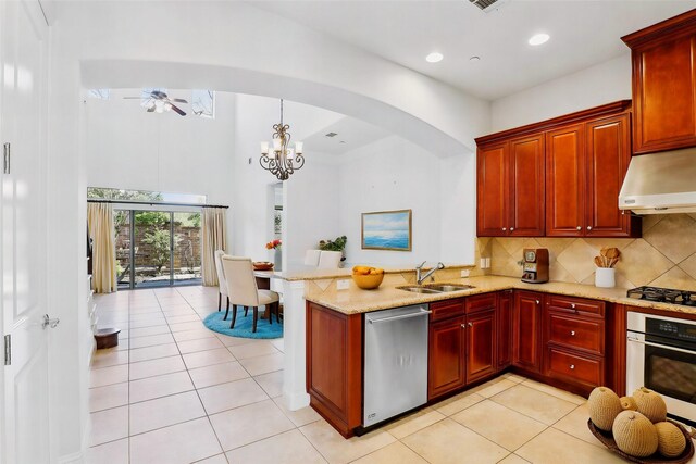 kitchen with arched walkways, stainless steel dishwasher, white oven, a sink, and under cabinet range hood