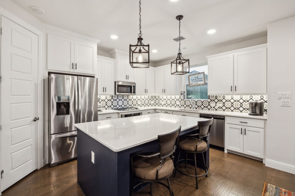 kitchen with a kitchen island, stainless steel appliances, dark wood finished floors, and a sink