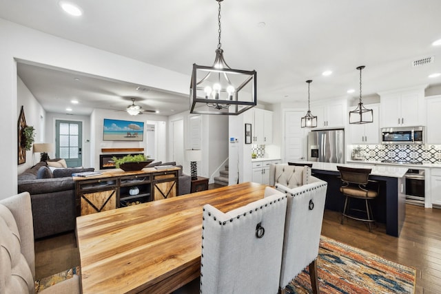9408 Lamar St Unit D, Rowlett, TX 75089 - dining area with ceiling fan, dark wood finished floors, recessed lighting, stairway, and a glass covered fireplace