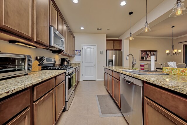 kitchen featuring light tile patterned flooring, a sink, stainless steel appliances, decorative light fixtures, and visible vents