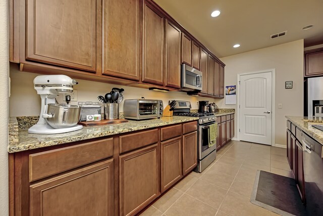 kitchen featuring light stone countertops, stainless steel appliances, light tile patterned floors, a toaster, and visible vents