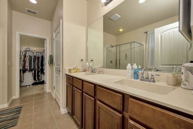 12521 Gritstone Dr, Denton, TX 76207 - bathroom featuring tile patterned floors, a shower stall, double vanity, baseboards, and a walk in closet