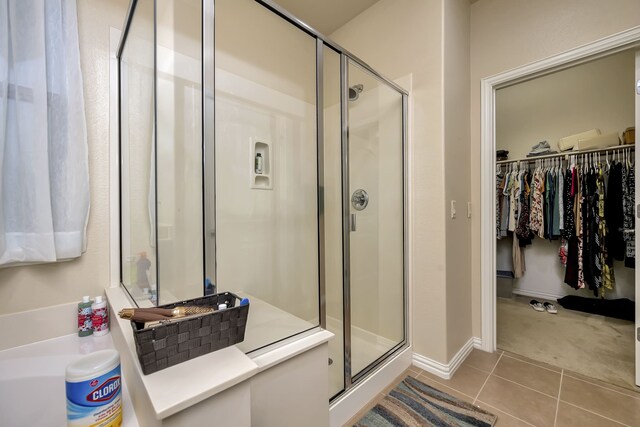 full bath featuring baseboards, a spacious closet, a shower stall, and tile patterned flooring