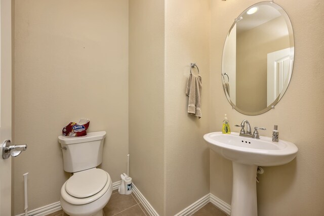 bathroom featuring toilet, baseboards, a sink, and tile patterned flooring