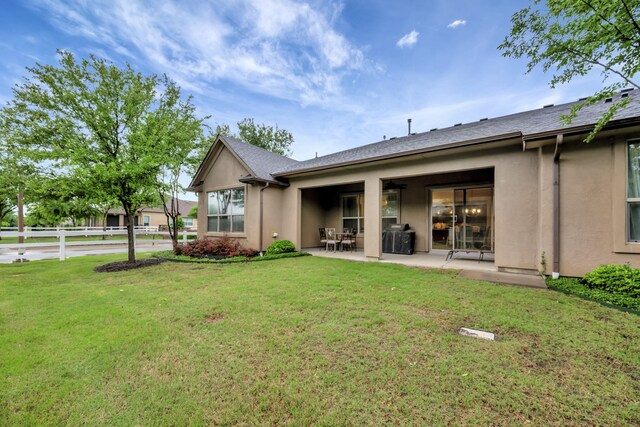 back of house with stucco siding, a yard, and a patio area