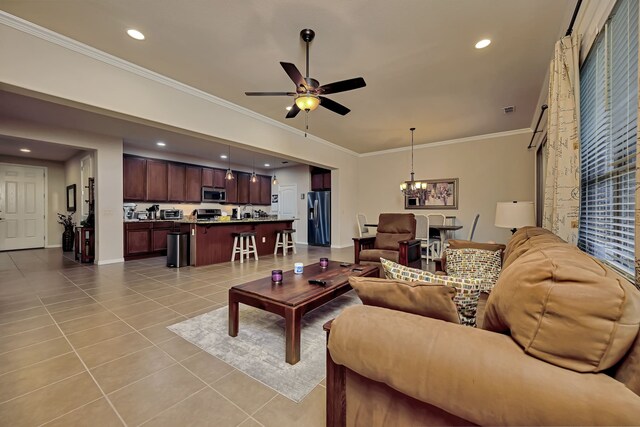 living room featuring visible vents, ornamental molding, baseboards, ceiling fan with notable chandelier, and light tile patterned floors