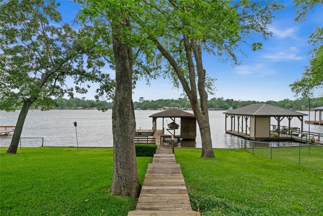 view of dock featuring a gazebo, boat lift, a water view, and a yard