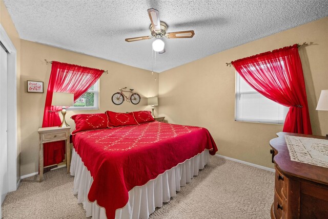 carpeted bedroom featuring baseboards, ceiling fan, and a textured ceiling