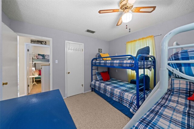 bedroom with a ceiling fan, carpet flooring, a textured ceiling, and visible vents
