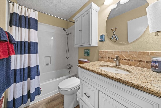 full bathroom featuring vanity, shower / bath combo with shower curtain, a textured ceiling, wood finished floors, and tasteful backsplash