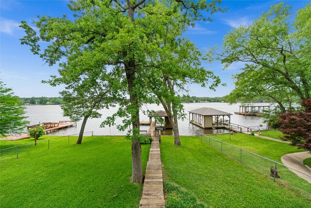 view of yard with a water view, fence, and a boat dock