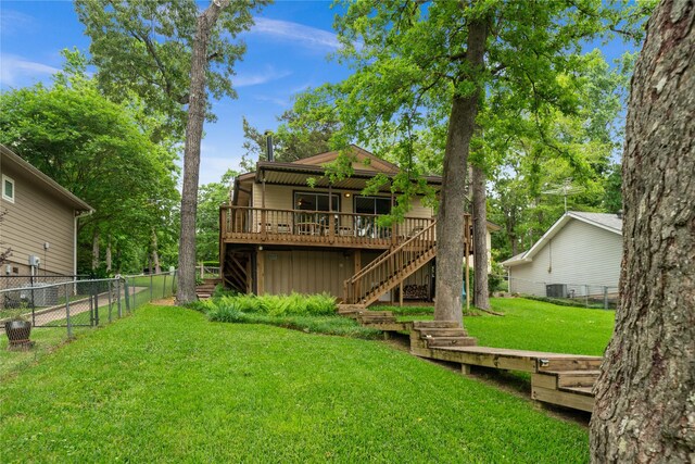 back of house featuring fence, stairs, a deck, central air condition unit, and a lawn