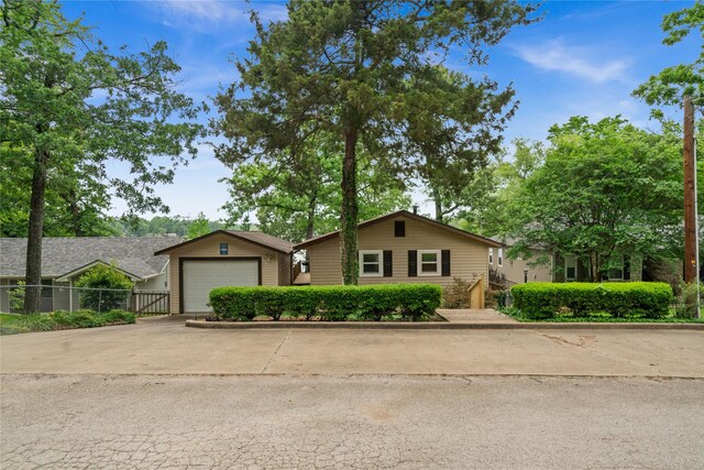 single story home featuring a garage, fence, an outdoor structure, and driveway