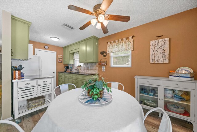 dining space with a textured ceiling, ceiling fan, visible vents, and dark wood-style floors