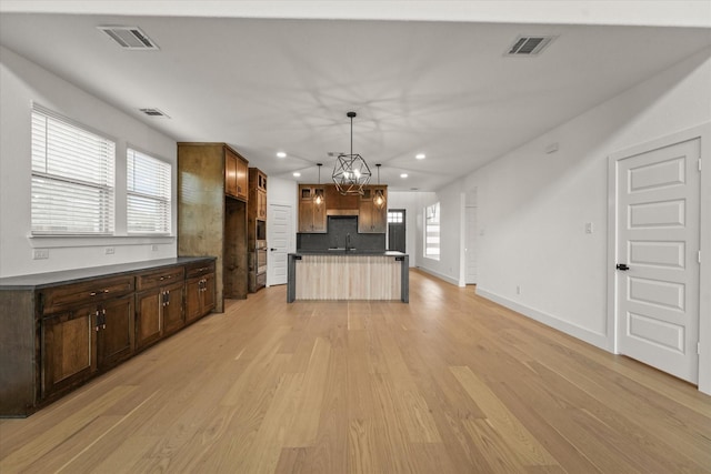 kitchen featuring a sink, light wood finished floors, a chandelier, recessed lighting, and visible vents