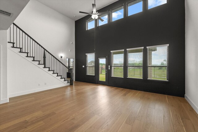 entrance foyer with a ceiling fan, visible vents, wood finished floors, stairway, and a high ceiling